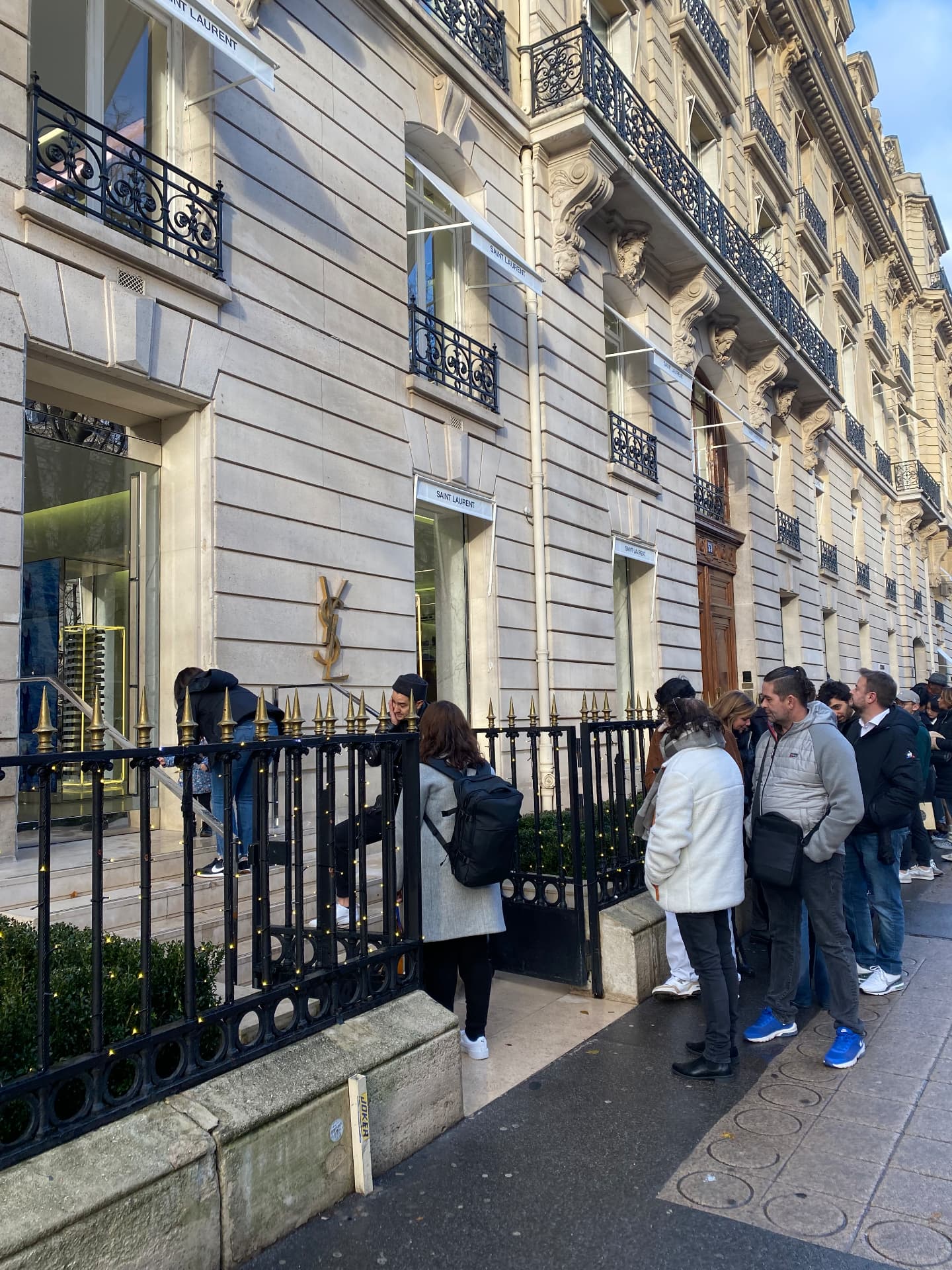 Shoppers waiting in line on a Paris avenue